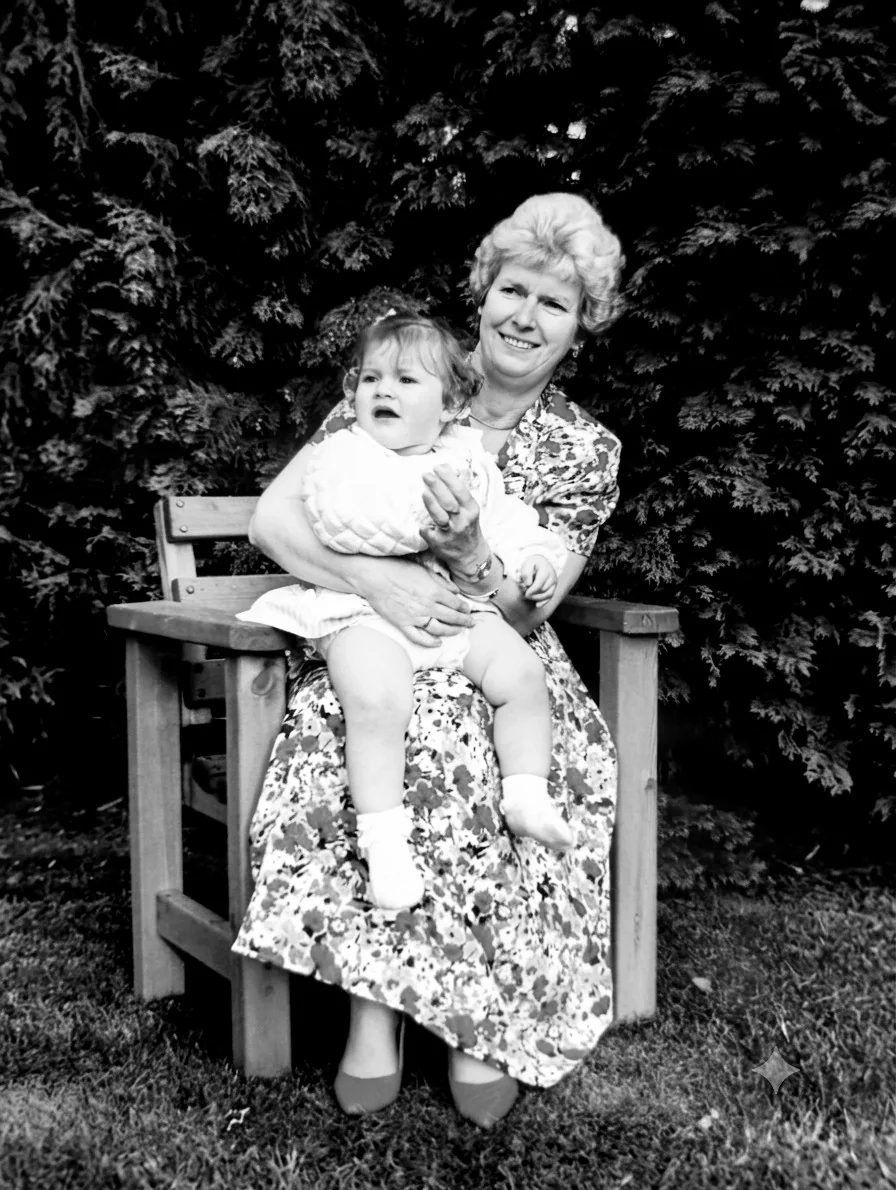 Black-and-white photograph of baby Gemma sitting on her grandmother Dorothy's knee in a garden